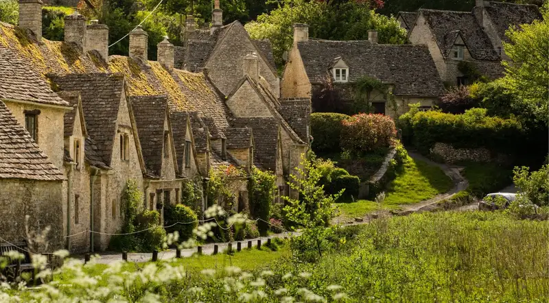 Arlington Row's line of historic honey-stone weavers' cottages in Bibury, the Cotswolds